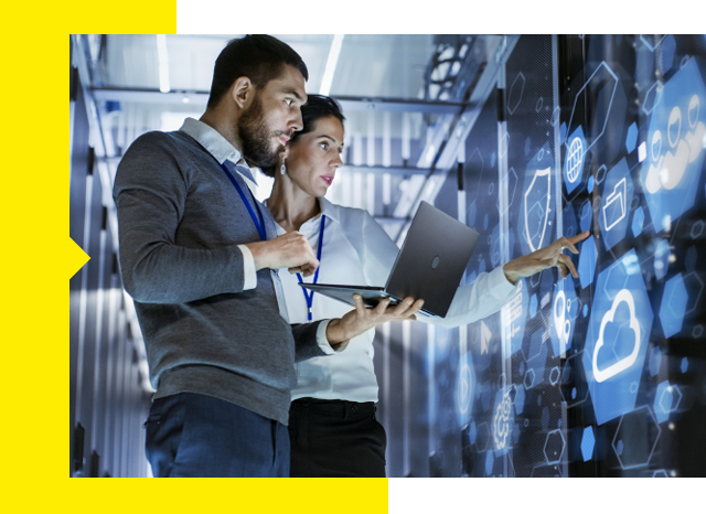 Two people focused on a laptop in a data center.